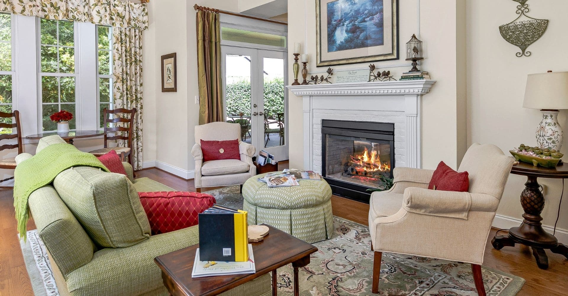 A cozy living room featuring a fireplace, comfortable seating, and decor with large windows.