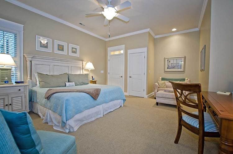 bed with aqua colored bedding and a seating area across from it