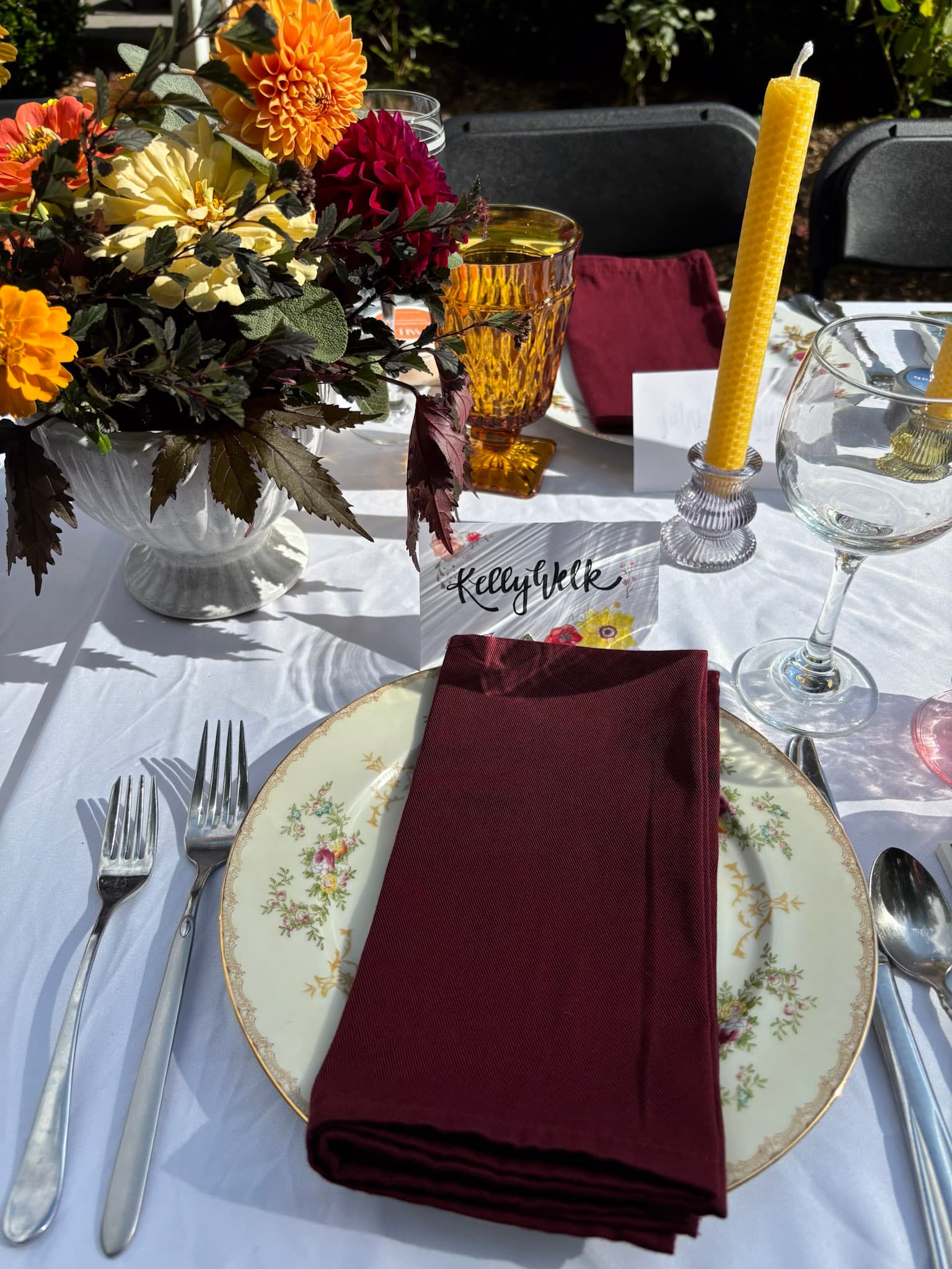 A beautifully set dining table featuring a floral centerpiece, elegant glassware, and place settings with burgundy napkins.
