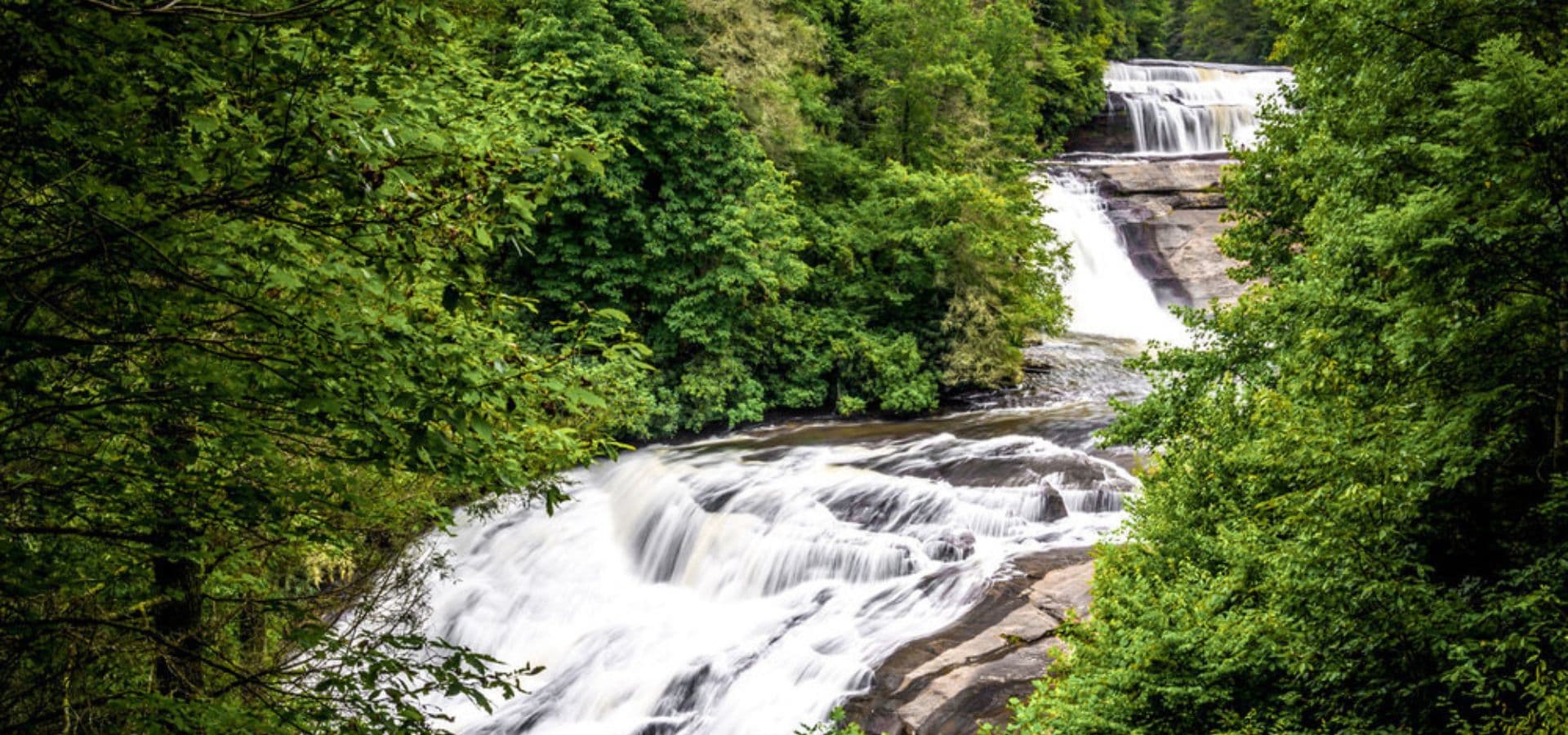 A cascading waterfall surrounded by lush green trees.