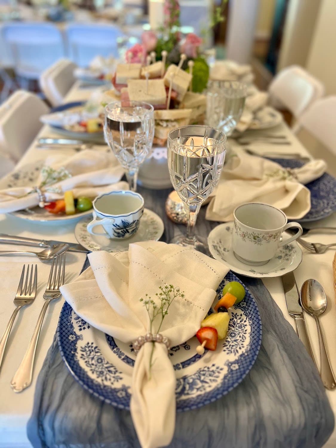 A beautifully set dining table featuring elegant tableware, decorative napkins, and a variety of foods.