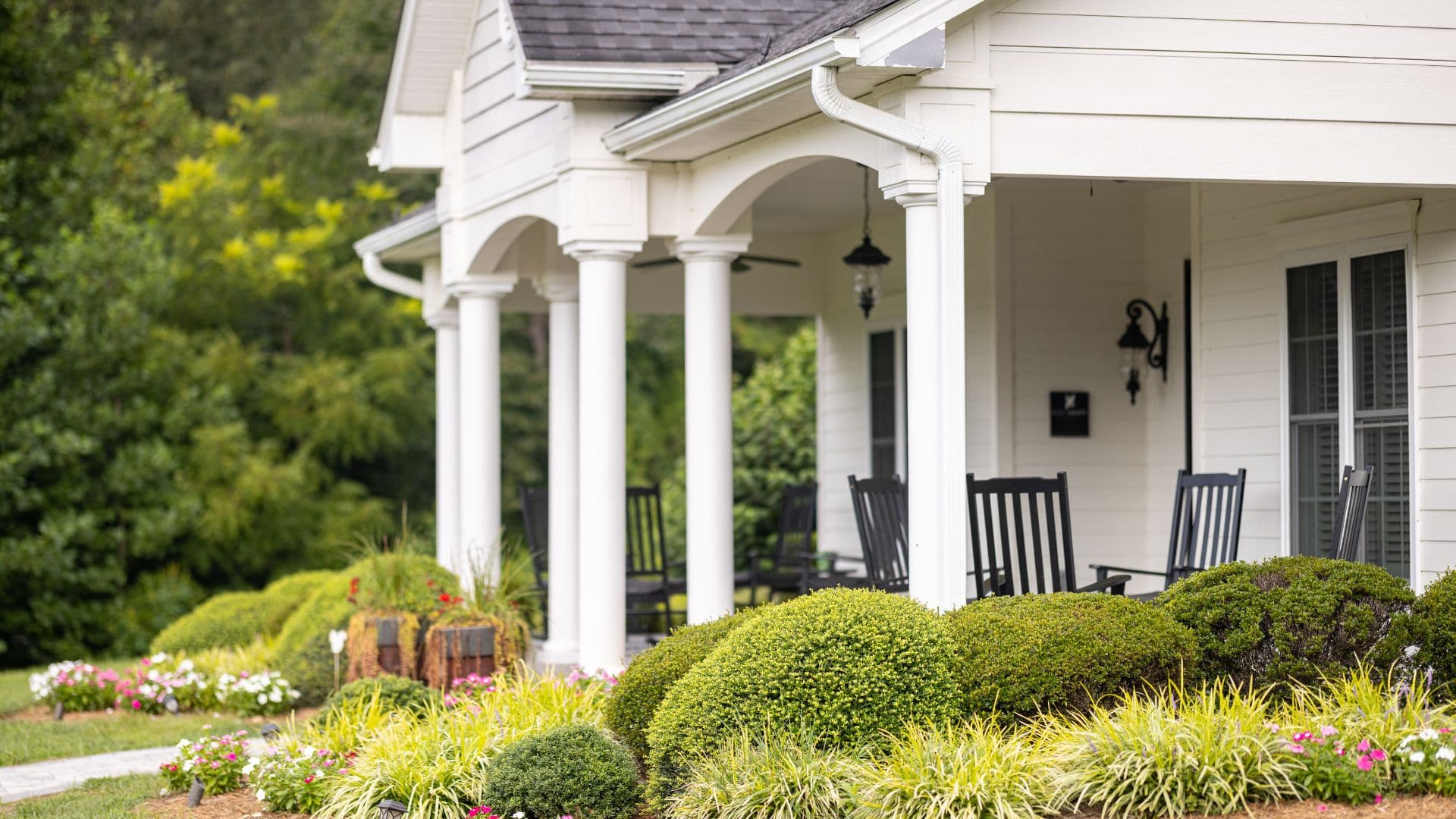 A charming porch featuring rocking chairs and well-manicured flower beds.