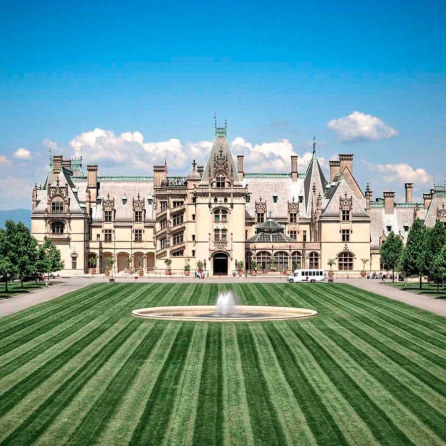 A grand mansion surrounded by a meticulously striped lawn and blue skies.